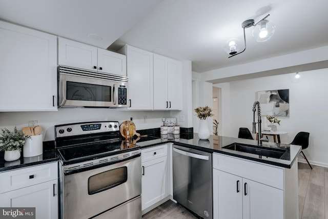 kitchen featuring appliances with stainless steel finishes, kitchen peninsula, sink, and white cabinets