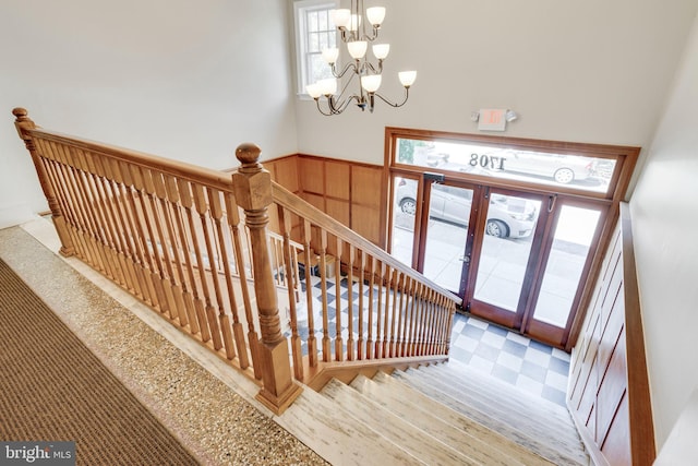 staircase with a notable chandelier and french doors