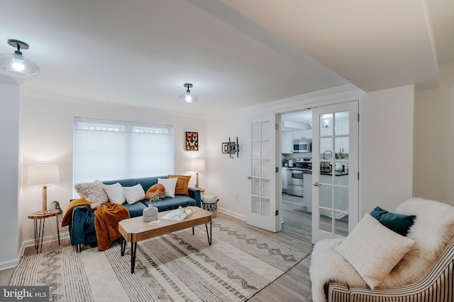 living room featuring ornamental molding, light hardwood / wood-style flooring, and french doors