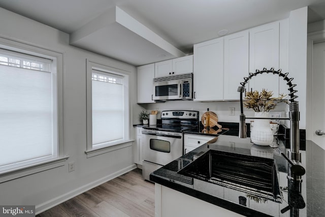 kitchen featuring stainless steel appliances, a wealth of natural light, and white cabinets