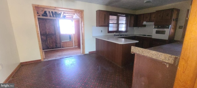 kitchen with sink, kitchen peninsula, and white oven