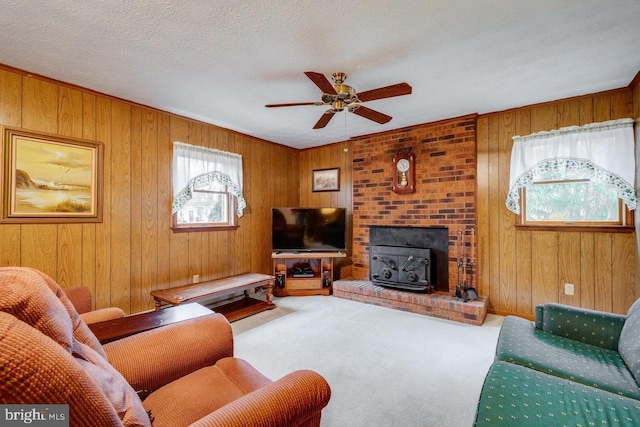 carpeted living room with ceiling fan, a healthy amount of sunlight, a textured ceiling, and wood walls