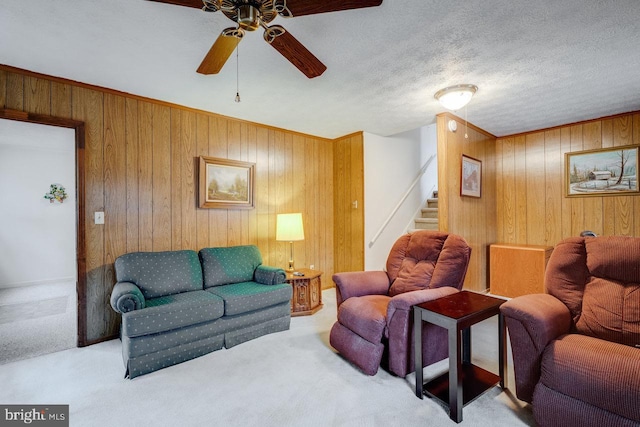 living room with light carpet, ceiling fan, a textured ceiling, and wood walls