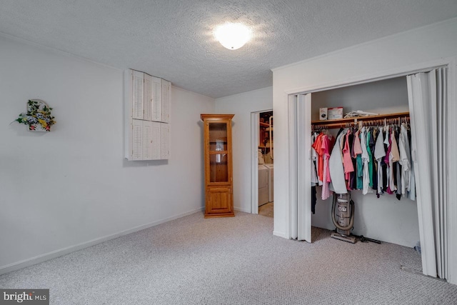 unfurnished bedroom with carpet floors, a textured ceiling, washer and clothes dryer, and a closet