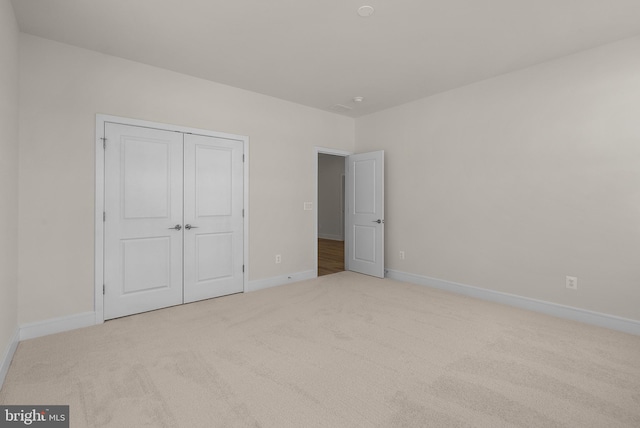 unfurnished bedroom with a closet and light carpet