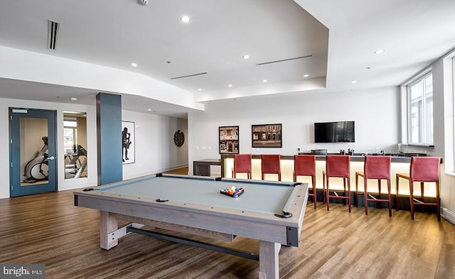 rec room with pool table, bar, and light wood-type flooring