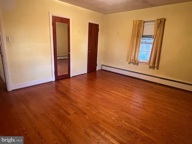 unfurnished bedroom with a baseboard heating unit and hardwood / wood-style floors