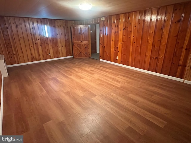 basement featuring wood-type flooring and wooden walls