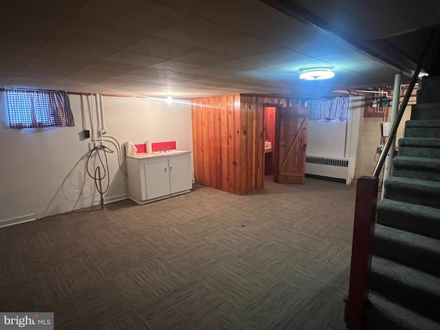 basement with radiator, wood walls, and carpet