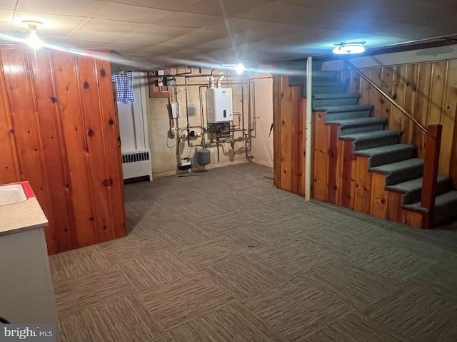 basement with wooden walls, radiator, carpet, and water heater