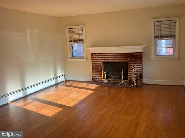 unfurnished living room featuring a healthy amount of sunlight, a baseboard radiator, wood-type flooring, and a tile fireplace