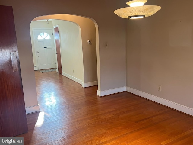 unfurnished room with hardwood / wood-style flooring and baseboard heating