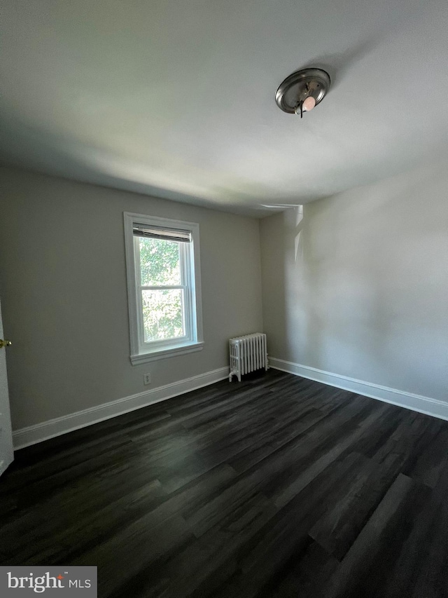 unfurnished room with radiator and dark hardwood / wood-style floors