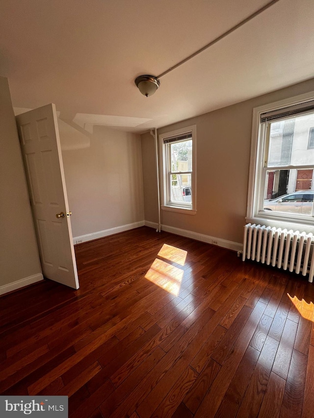 unfurnished bedroom with dark hardwood / wood-style floors and radiator heating unit