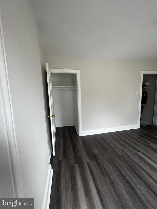 unfurnished bedroom featuring dark wood-type flooring and a closet