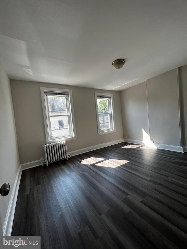 unfurnished room with radiator and dark hardwood / wood-style floors