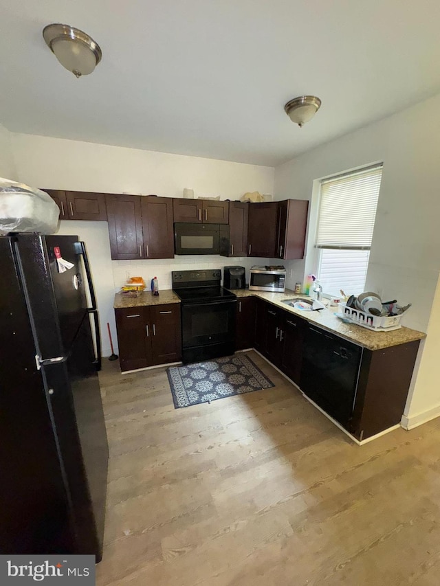 kitchen with dark brown cabinetry, sink, light wood-type flooring, and black appliances