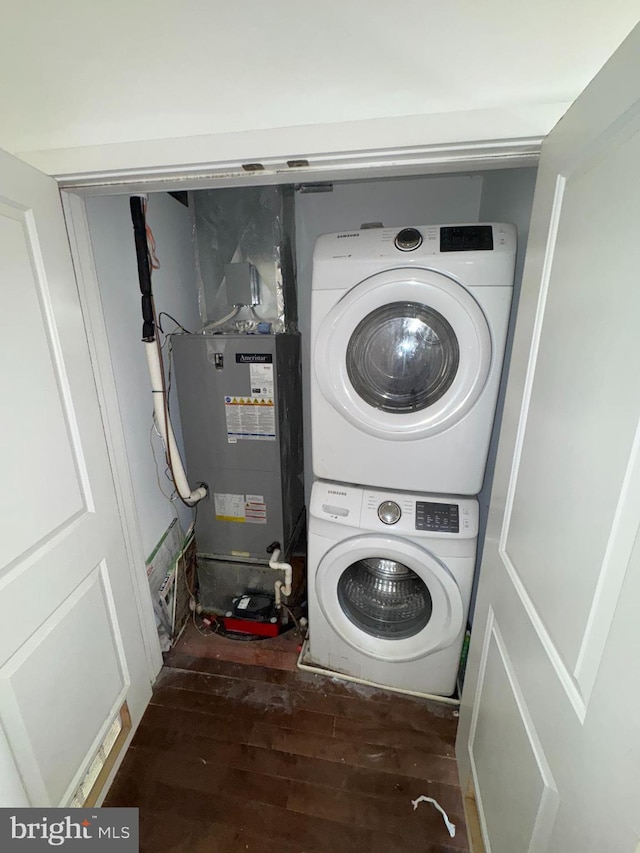 laundry room featuring dark wood-type flooring and stacked washing maching and dryer