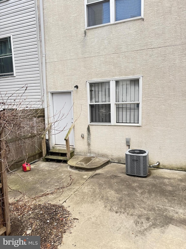 rear view of property with cooling unit and a patio