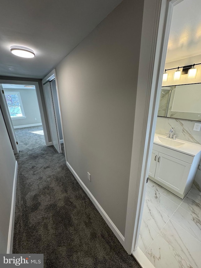 corridor featuring sink and light carpet