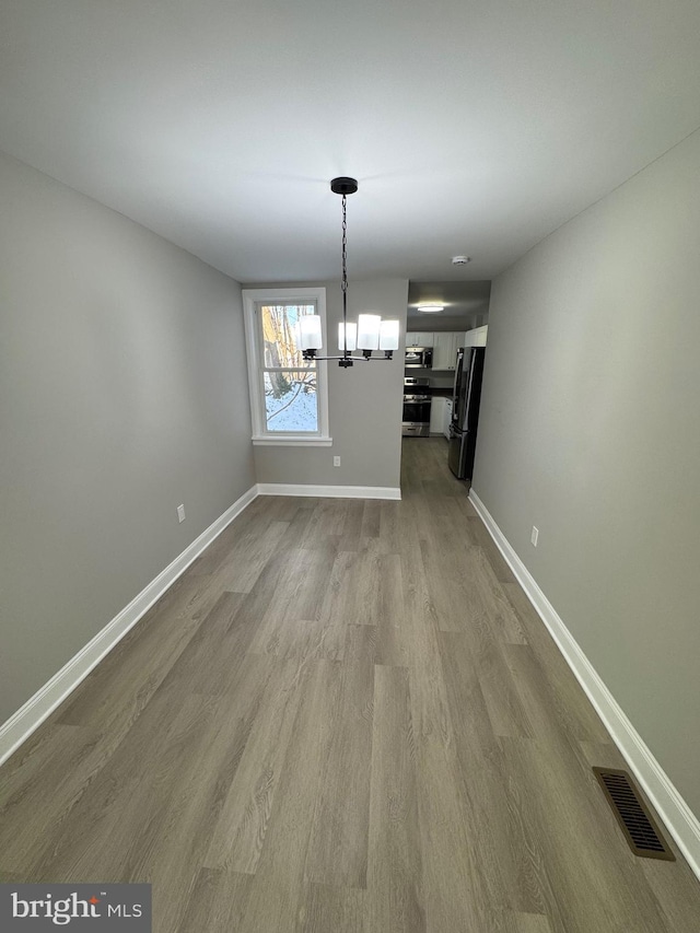 unfurnished dining area featuring a notable chandelier and light hardwood / wood-style floors