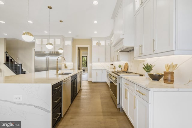 kitchen featuring white cabinetry, an island with sink, sink, hanging light fixtures, and high end appliances