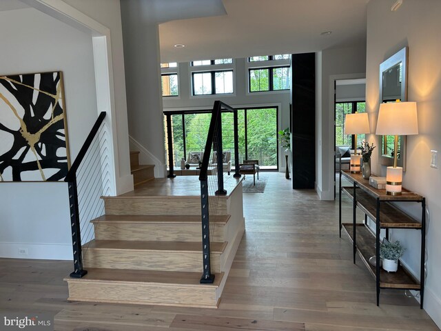 stairs with wood finished floors, baseboards, recessed lighting, and a high ceiling
