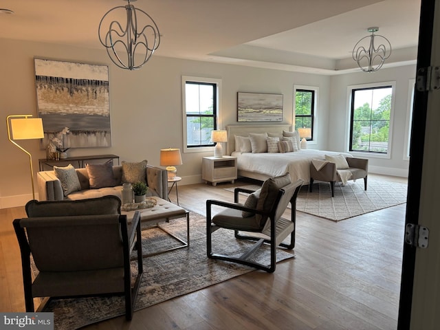 bedroom with a chandelier, multiple windows, wood finished floors, and baseboards