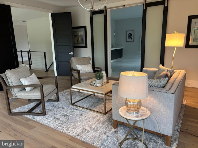 living room featuring a barn door, wood finished floors, and baseboards