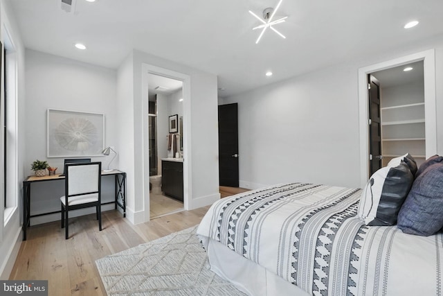 bedroom featuring light wood finished floors, recessed lighting, a walk in closet, baseboards, and ensuite bathroom