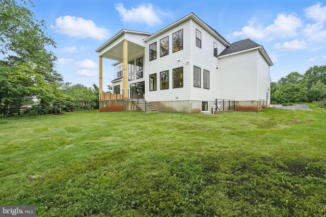 rear view of property with a yard and a balcony