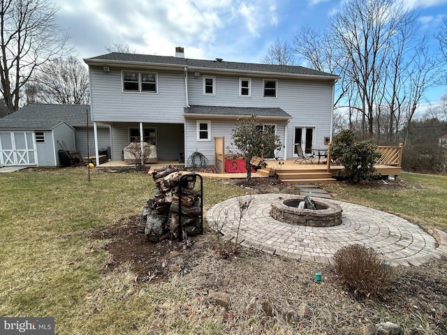 rear view of house featuring a wooden deck, a fire pit, a storage shed, and a yard