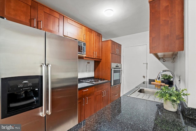 kitchen featuring appliances with stainless steel finishes, sink, and dark stone counters