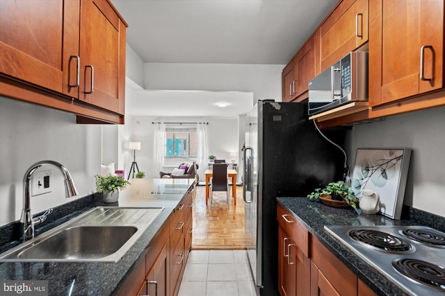 kitchen featuring light tile patterned floors, appliances with stainless steel finishes, sink, and dark stone counters