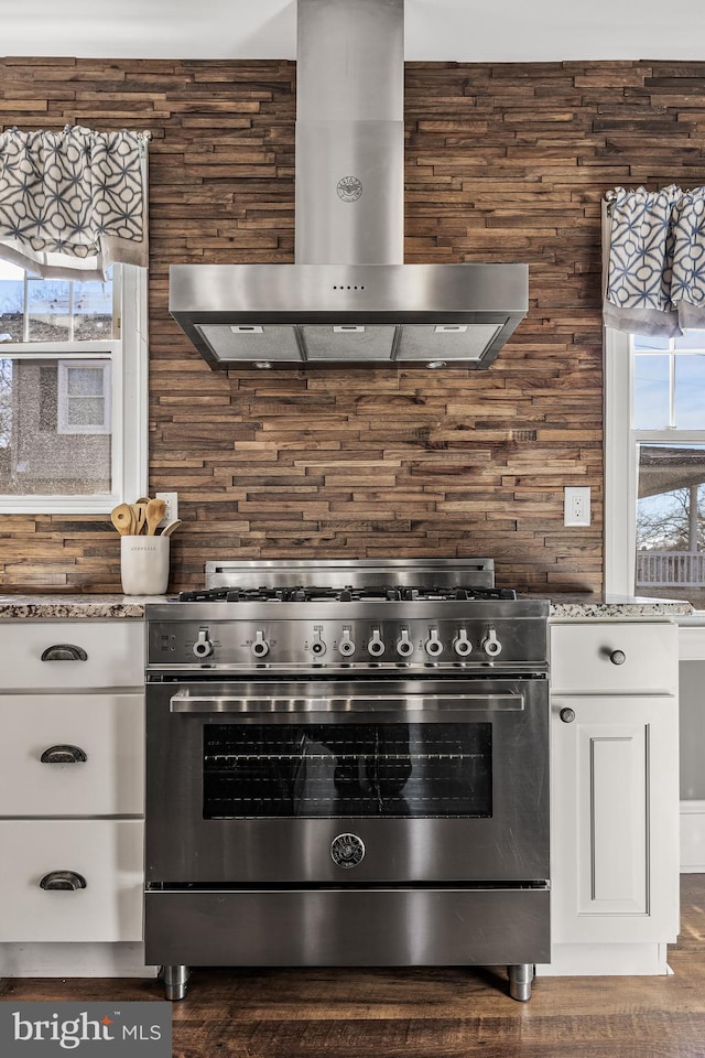 kitchen featuring stone countertops, white cabinetry, high end range, and exhaust hood