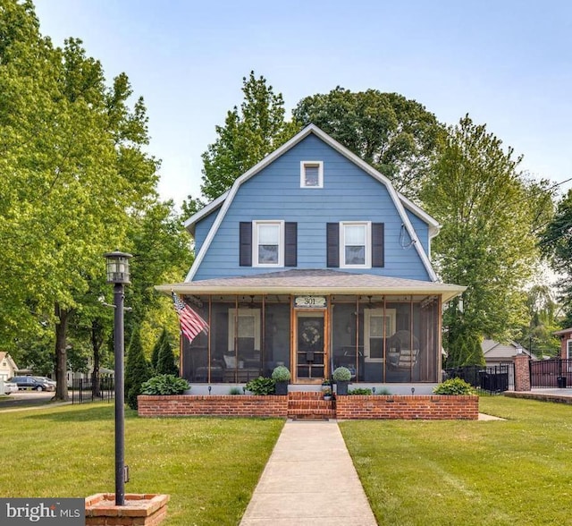 dutch colonial with a sunroom, a front yard, and a gambrel roof