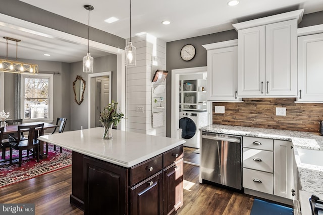 kitchen featuring decorative light fixtures, washer / clothes dryer, stainless steel dishwasher, dark wood-type flooring, and white cabinetry