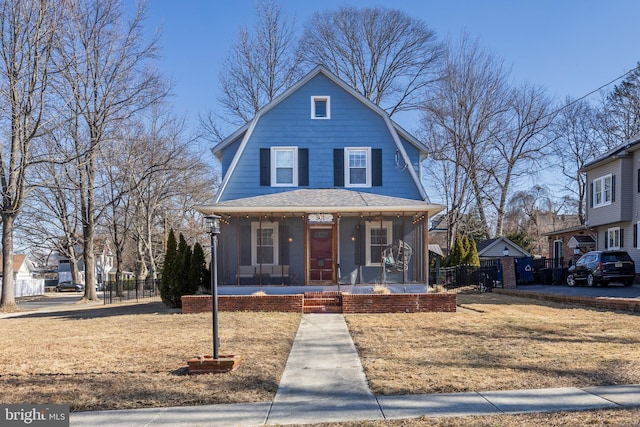 dutch colonial with a sunroom, roof with shingles, fence, and a gambrel roof