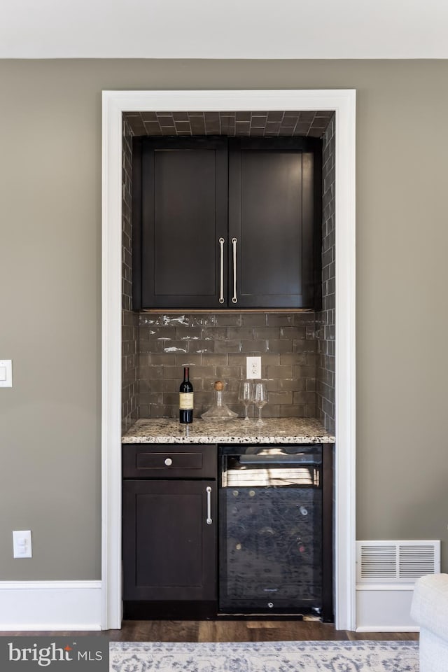 bar featuring a bar, beverage cooler, visible vents, and tasteful backsplash