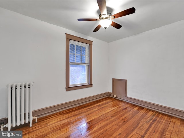 empty room with light hardwood / wood-style flooring, radiator heating unit, and ceiling fan