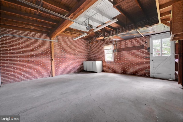 misc room featuring brick wall and concrete flooring