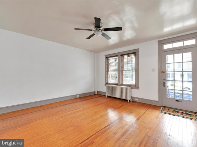 empty room with radiator, ceiling fan, and light wood-type flooring