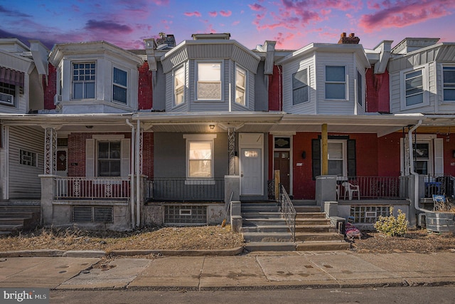 multi unit property featuring a porch and brick siding