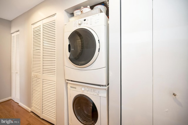 clothes washing area with stacked washing maching and dryer and wood-type flooring