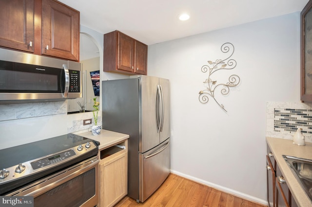 kitchen with tasteful backsplash, stainless steel appliances, and light wood-type flooring