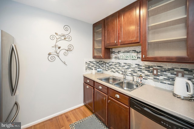 kitchen featuring stainless steel appliances, sink, backsplash, and light hardwood / wood-style floors