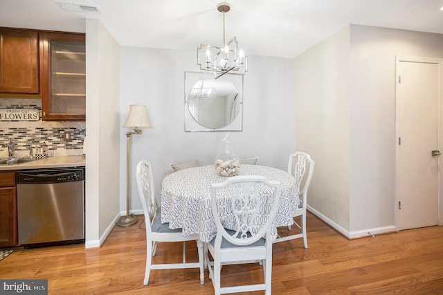 dining space with an inviting chandelier, sink, and light hardwood / wood-style floors