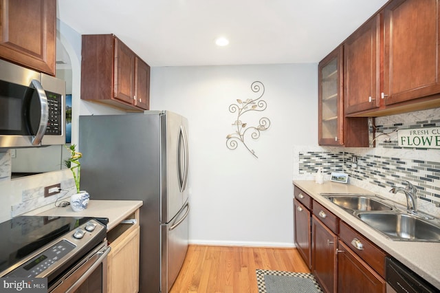 kitchen featuring sink, decorative backsplash, light hardwood / wood-style flooring, and stainless steel appliances