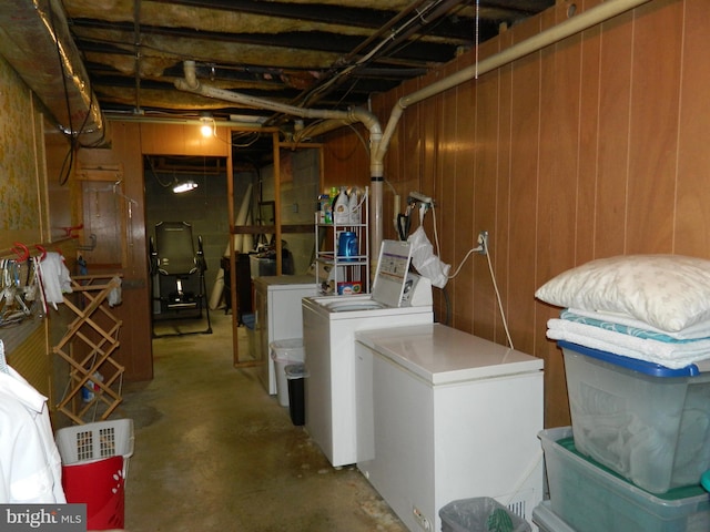 basement featuring wooden walls, washing machine and clothes dryer, and refrigerator