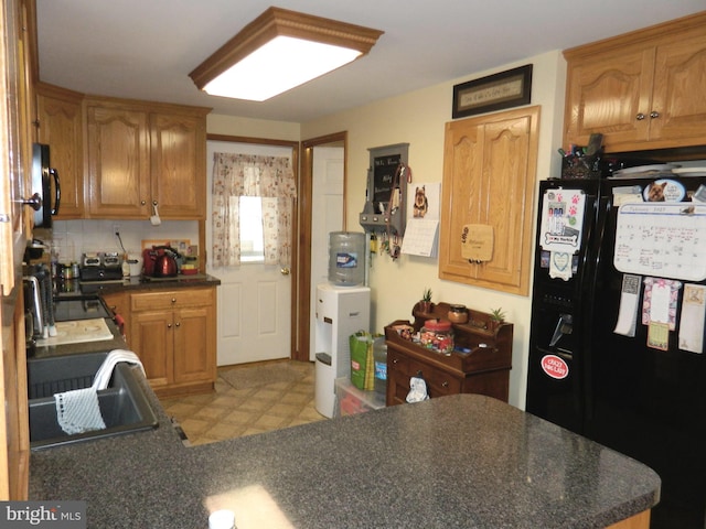 kitchen with black refrigerator with ice dispenser and decorative backsplash